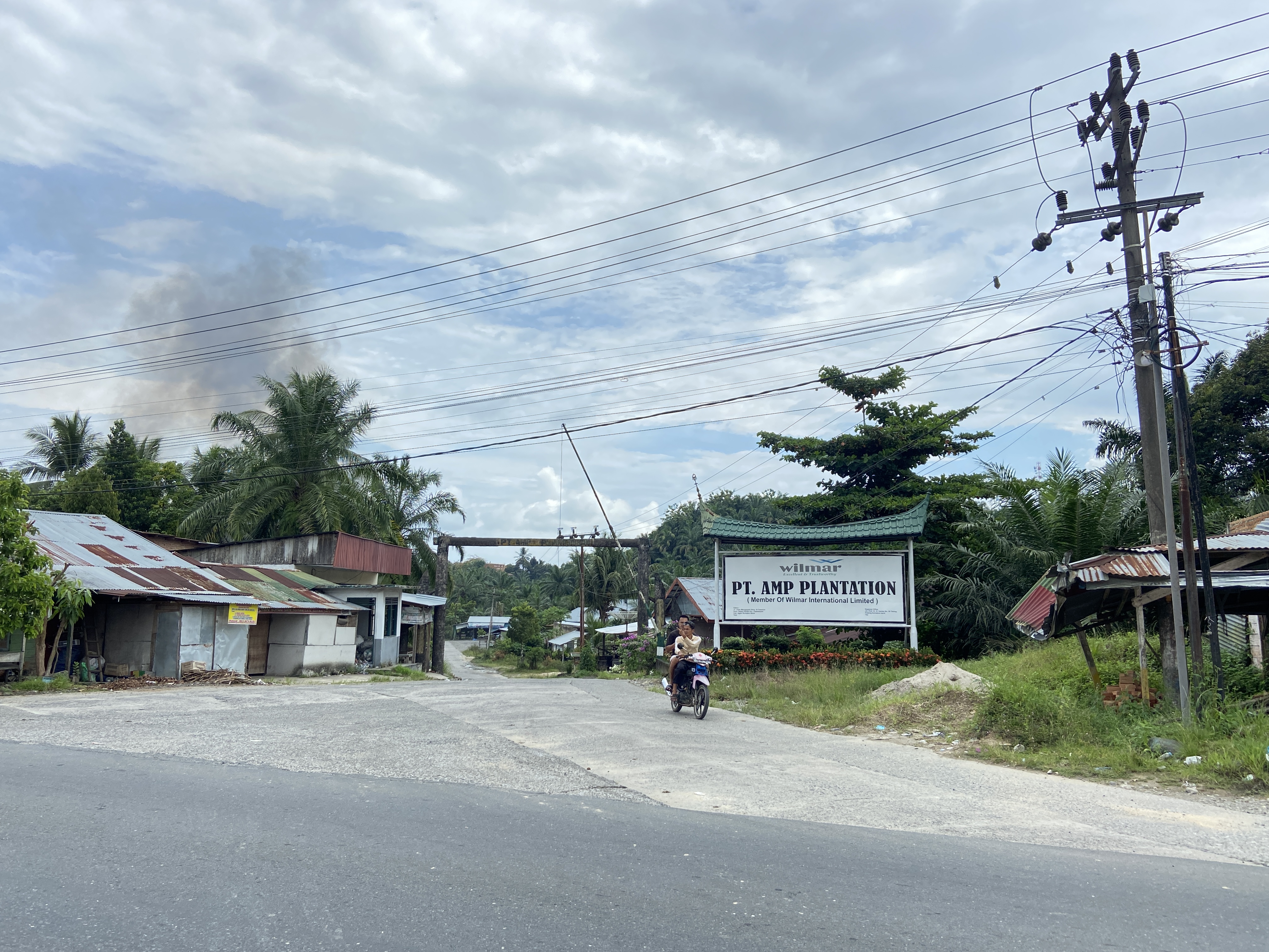 Pengendara sepeda motor melintas di depan pintu masuk PT Agra Masang Plantation, Kabupaten Agam, Rabu, 22/7/2026. Perkebunan sawit anak usaha Wilmar Group itu berada di lanskap DAS yang terdampak banjir bandang pada November 2025.